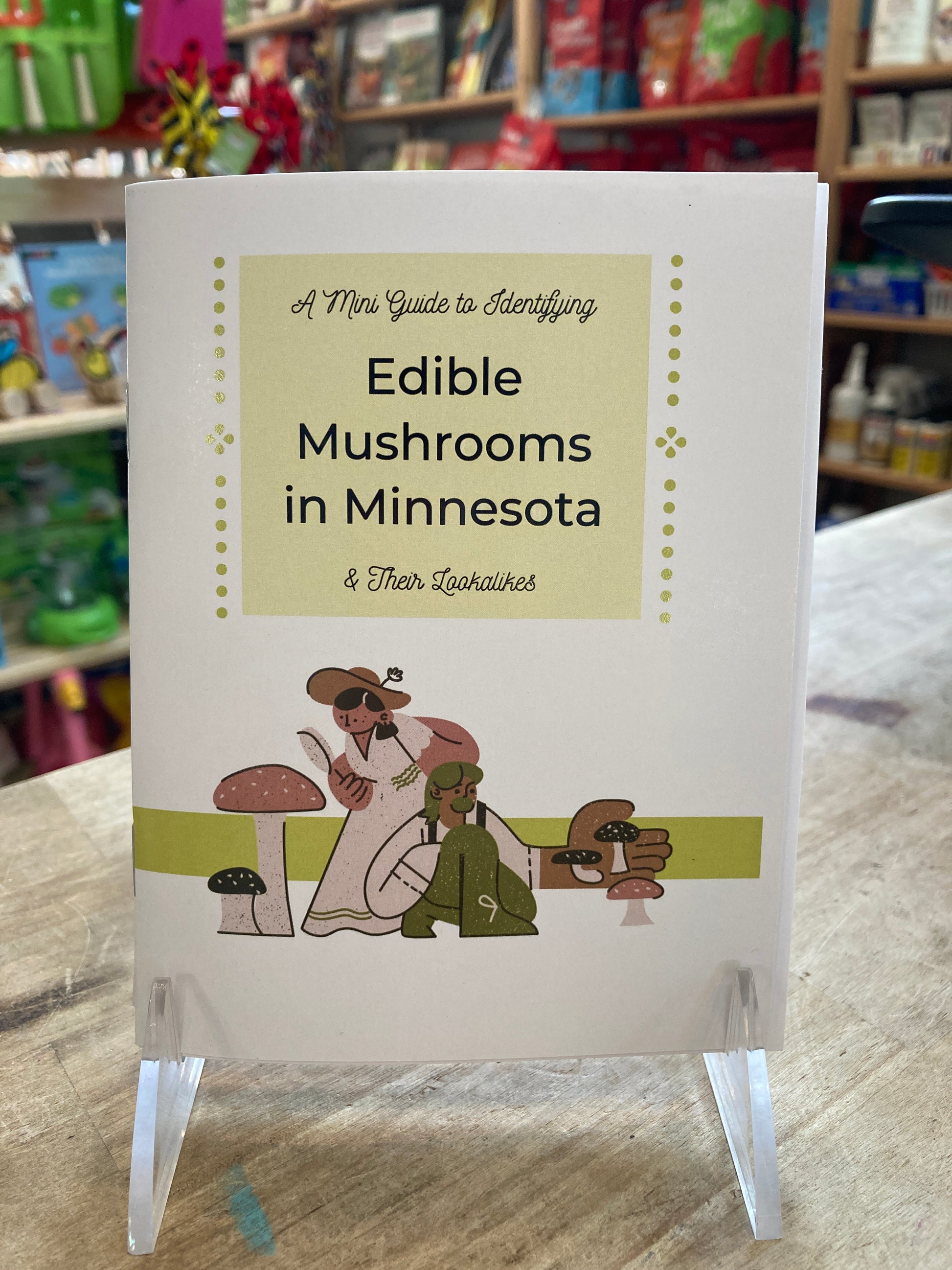 Small paper zine reading "A Mini Guide to Identifying Edible Mushrooms in Minnesota and Their Lookalikes." Illustrations of two people looking at mushrooms.