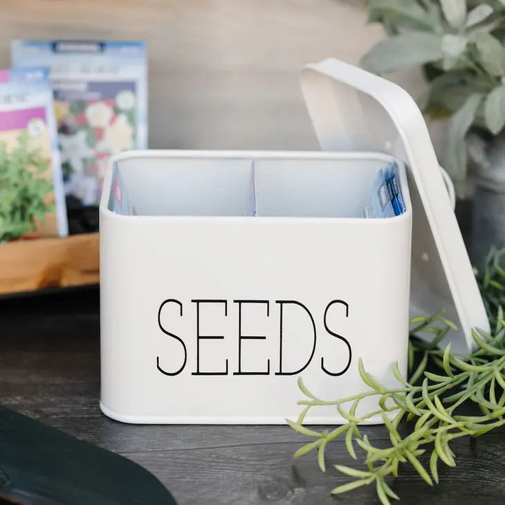 White metal bin with "seeds" in all capitals on side. Bin has one divider in the middle.