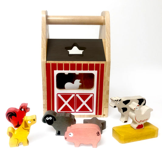 A toy wooden barn surrounded by a wooden rooster, dog, sheep, pig, hen, cow, star, and block. The barn has openings in the shape of each item.