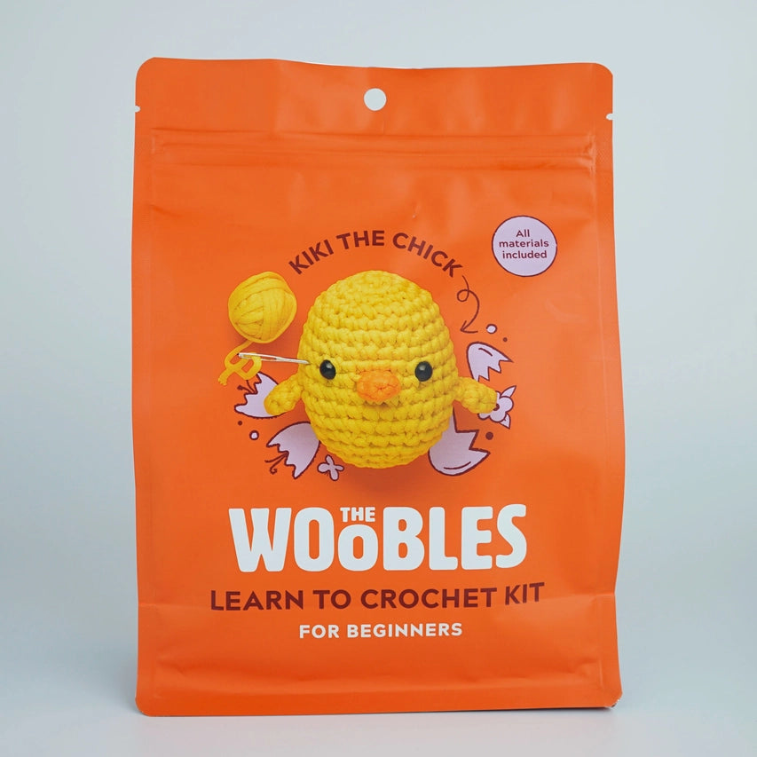 An orange package with an image of an oval-shaped yellow crocheted chick. Text reads "The Woobles learn to crochet kit for beginners."