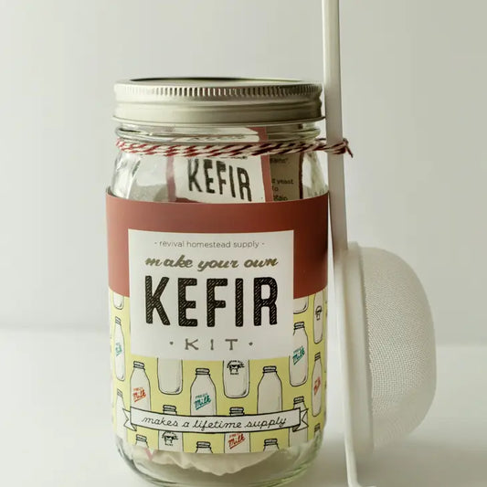 Wide-mouth quart-sized mason jar with "Make your own kefir" label. A mesh strainer is tied to the jar.